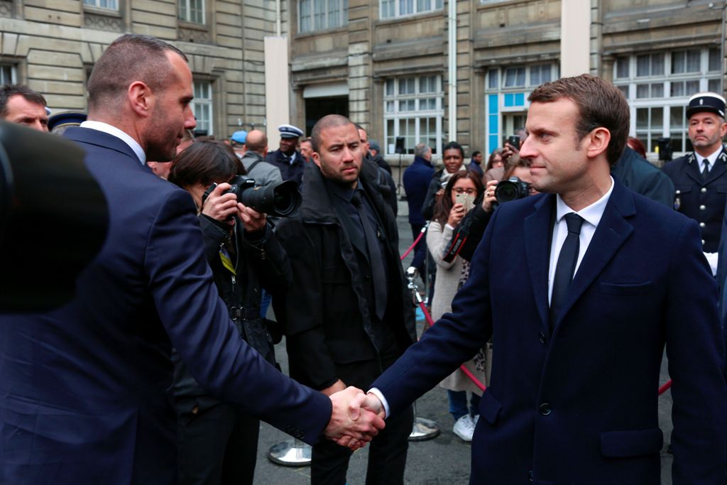French centrist presidential candidate Emmanuel Macron (R) shakes hands with Etienne Cardiles, the partner of the policeman killed by a jihadist in an attack on the Champs Elysees, on April 25, 2017, during a ceremony at the Paris prefecture building. AFP