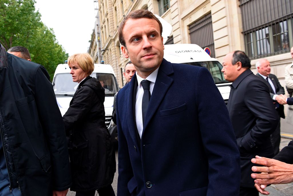 French presidential election candidate for the En Marche ! movement, Emmanuel Macron (C) leaves the Paris Police Prefecture building after attending a ceremony honouring the policeman killed by a jihadist in an attack on the Champs Elysees, on April 25, 2