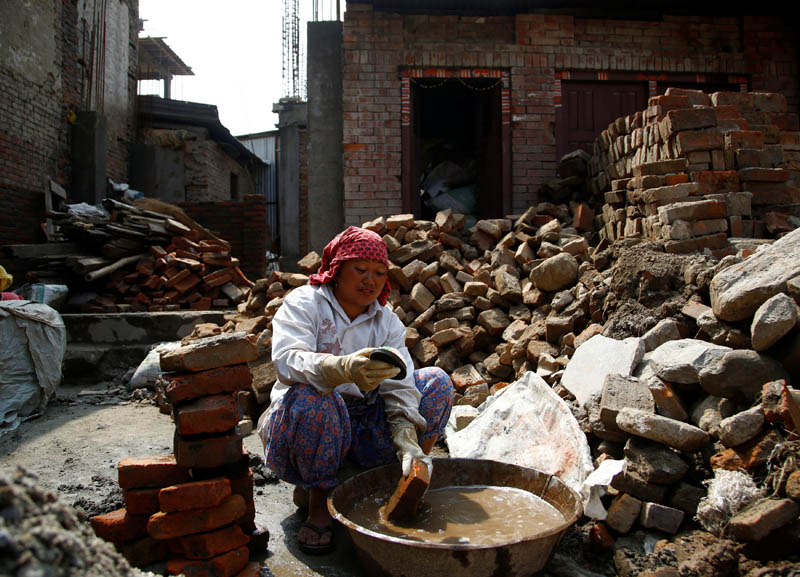 A woman cleans bricks collected from her house that collapsed during the 2015 earthquake, to rebuild her house in Bhaktapur, Nepal, on April 21, 2017. Photo: Reuters