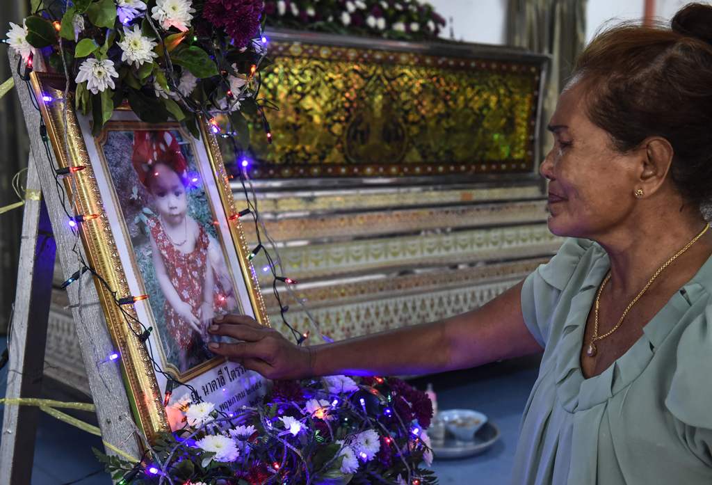 Jiranuch Trirat's mother touches a photo of her slain 11-month old granddaughter Natalie at a temple in Phuket on April 27, 2017.   AFP / LILLIAN SUWANRUMPHA