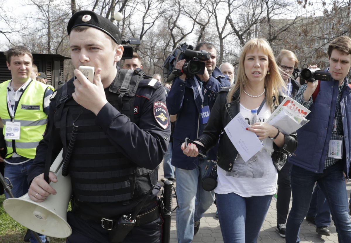 Open Russia movement coordinator Maria Baronova (2nd R), surrounded by journalists and an Interior Ministry officer, walks during a protest, calling for Russian President Vladimir Putin not to run for another presidential term next year, in central Moscow
