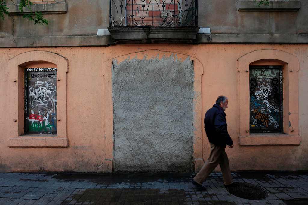 A man passes by a bricked up entrance to a building in Barcelona on April 28, 2017. AFP / PAU BARRENA
