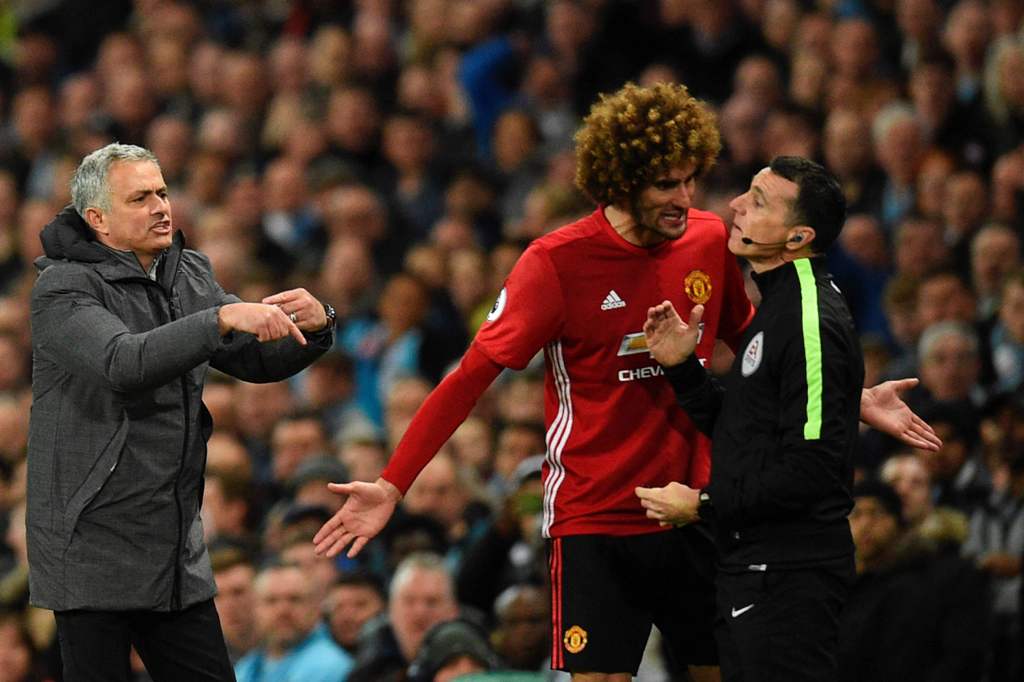 Manchester United's Portuguese manager Jose Mourinho (L) indicates he wants to make a substitution as Manchester United's Belgian midfielder Marouane Fellaini (C) talks to fourth official Neil Swarbrick (R) after Fellaini was sent off during the English P