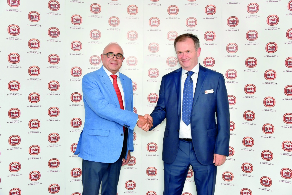 Baladna Company and Ali Bin Ali Group representatives shake hands at the signing ceremony.