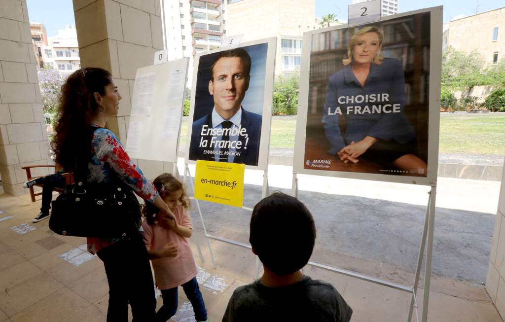 French citizens residing in Lebanon look at the election posters of independent centrist French presidential candidate Emmanuel Macron (L) and far-right Front National (FN - National Front) candidate Marine Le Pen, as they arrive to cast their votes at th