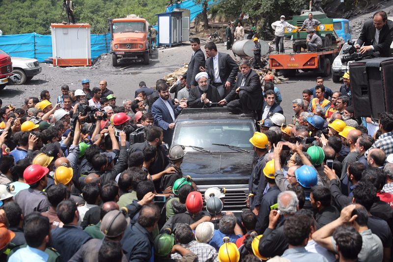 A handout picture provided by the office of Iranian President Hassan Rouhani on May 7, 2017 shows him (C) sitting through the roof of a car, visiting and speaking with coal miners and rescue workers at the scene of a coal mine which suffered from an explo