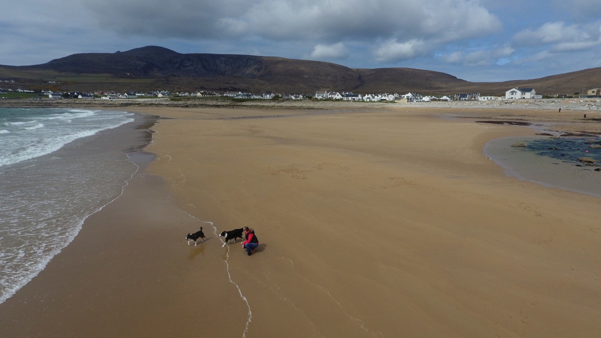 A woman walks her dogs along Dooagh beach after a storm returned sand to it, 30 years after another storm had stripped all the sand off the beach, on Achill island, County Mayo, Ireland, May 5, 2017. Picture taken May 5, 2017. MANDATORY CREDIT Sean Molloy