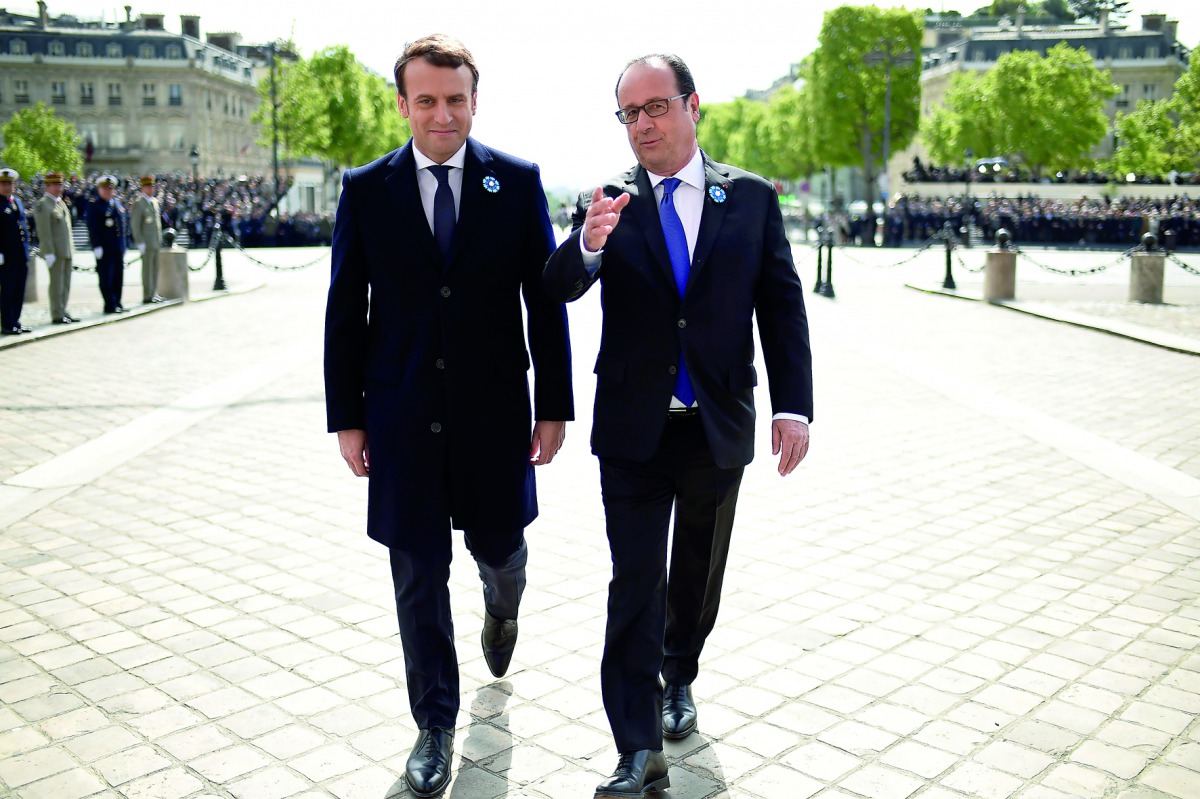 Outgoing French president Francois Hollande (right) and French president-elect Emmanuel Macron talk as they walk during the ceremony marking the 72nd anniversary of the victory over Nazi Germany during WWII on May 8, 1945 under the Arc de Triomphe monumen