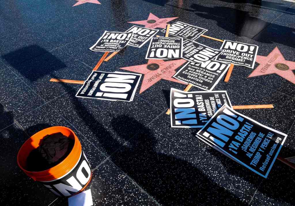 Protest posters are placed at President Donald Trump's star on the Hollywood Walk of Fame as members of Refuse Fascism protest the firing of FBI director James Comey by US President Donald Trump in Los Angeles, California on May 11, 2017. / AFP / RINGO CH