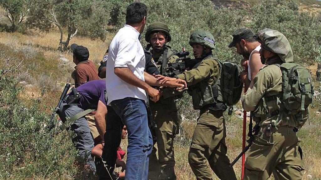 A Palestinian boy is being held by Israeli security forces for a while after a Palestinian agricultural land was set on fire by a group of Jewish settlers in Burin district of Nablus, West Bank on May 10, 2017. / AA.