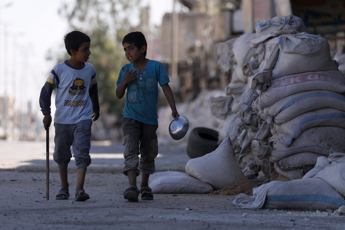 Boys walk near stacked sandbags in the town of Tabqa, after Syrian Democratic Forces (SDF) captured it from Islamic State militants this week, Syria May 12, 2017. Reuters/Rodi Said