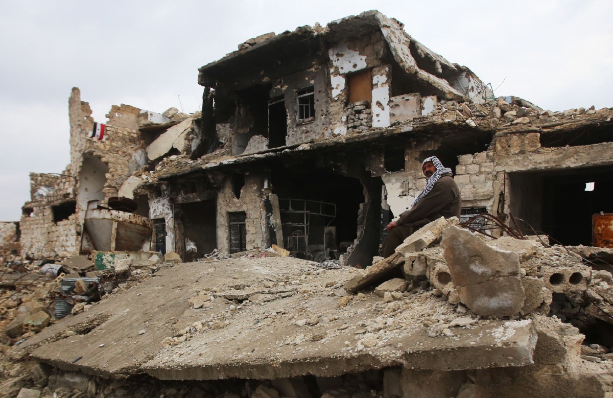 FILE PHOTO: A Syrian man sits on the rubble of his house in Al-Arkoub neighbourhood of Aleppo on December 17, 2016 after pro-government forces retook the area from rebel fighters (AFP / Youssef KARWASHAN) 