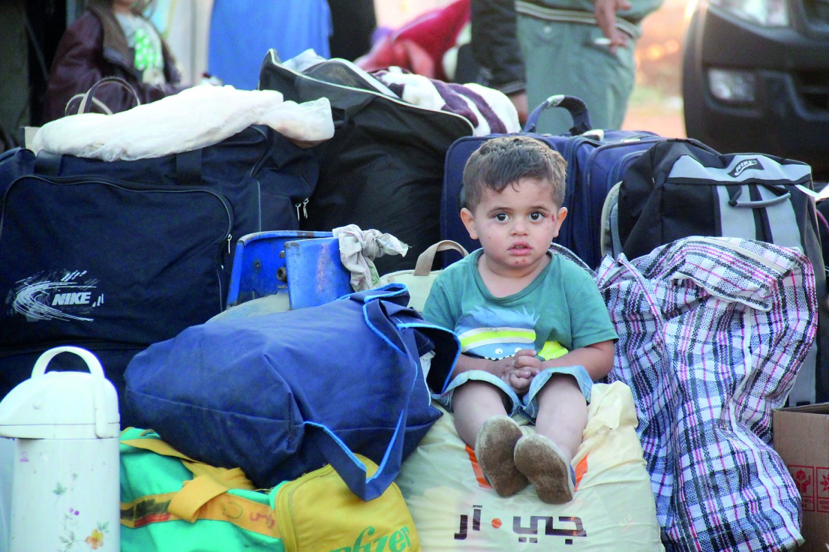 A Syrian child who was a part of a convoy of opposition fighters and their families, evacuated from the Waer neighbourhood, the last opposition-held district in the central city of Homs, sits after their arrival in the Maaret Al Ikhwaan village north of I