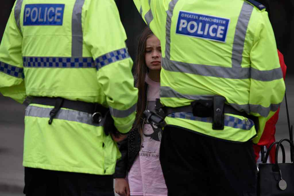 A woman and a young girl wearing a t-shirt of US singer Ariana Grande talks to police near Manchester Arena following a deadly terror attack in Manchester, northwest England on May 23, 2017.  AFP / Oli SCARFF
