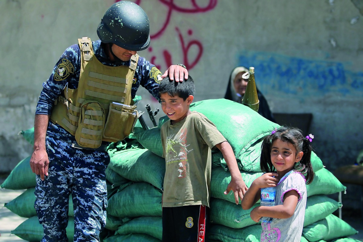 A member of the Iraqi forces plays with children on the outskirts of the old city of Mosul, yesterday, after the area was retaken by Iraqi forces during the ongoing offensive to clear it from Islamic State group fighters.