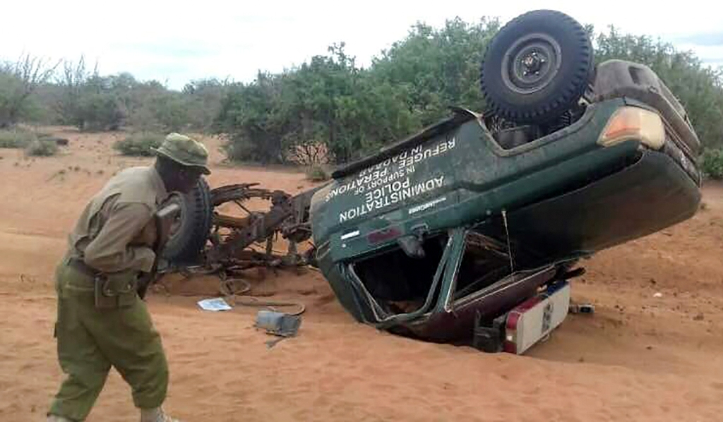 A picture taken with a mobile photo on May 25, 2017 shows a policeman looking at the wreckage of a police vehicle following a road side bomb in Garissa, northeastern Kenya.  AFP 
