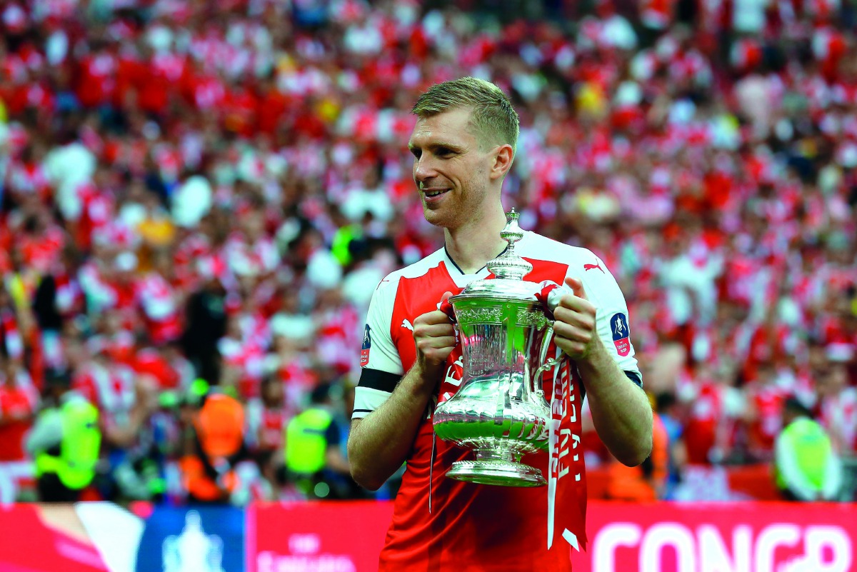 Arsenal's German defender Per Mertesacker holds the trophy as he celebrates on the pitch after their win over Chelsea in the English FA Cup final against Chelsea at Wembley Stadium in London on Saturday. 