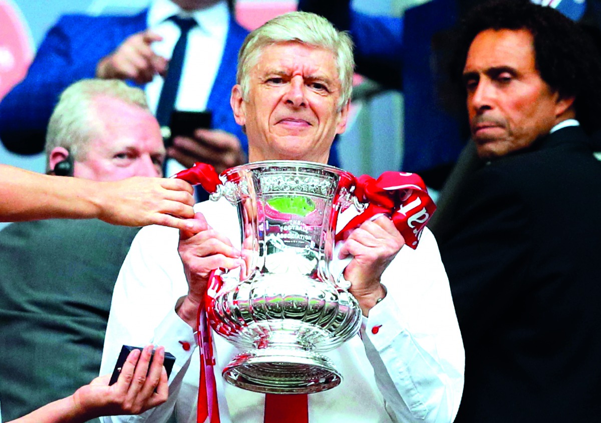Arsenal manager Arsene Wenger smiles as he holds the FA Cup trophy after their win over Chelsea in the final match at Wembley Stadium in London in this May 27 file picture.