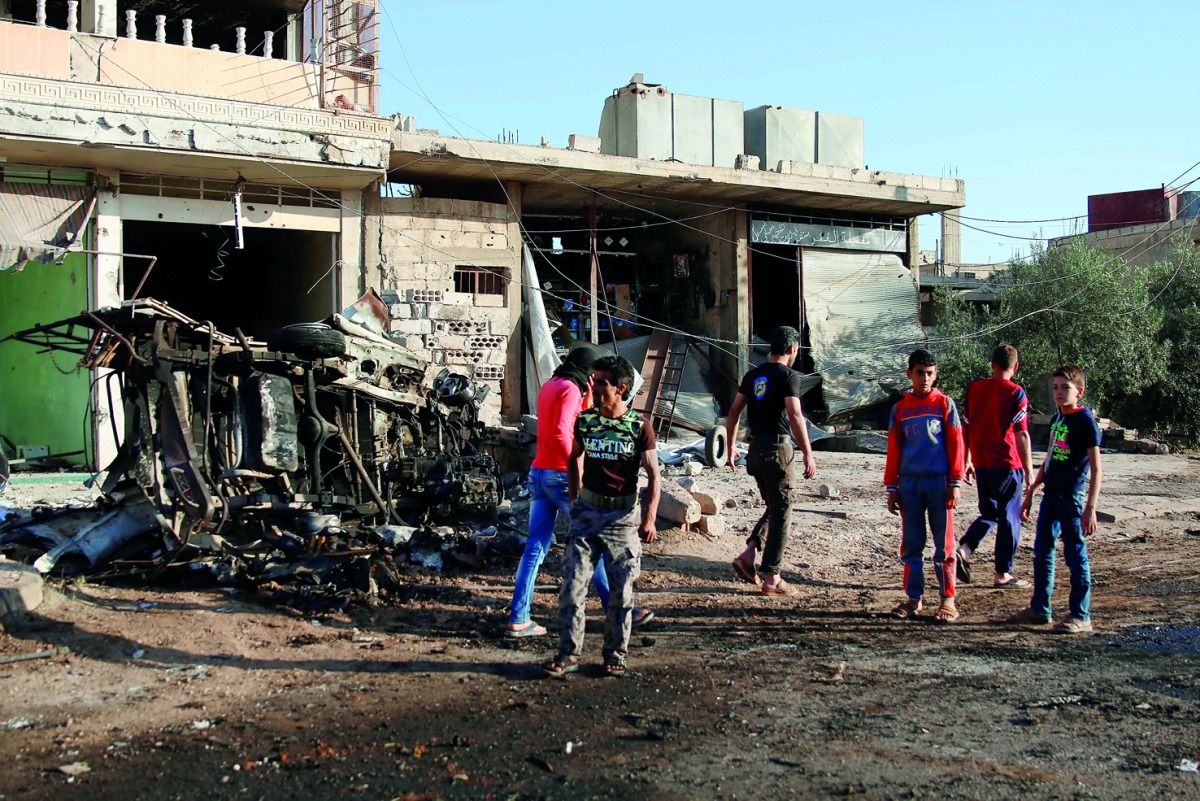 People walk at a site hit by an air strike in the rebel-held Tafas town, in Deraa Governorate, Syria, yesterday.