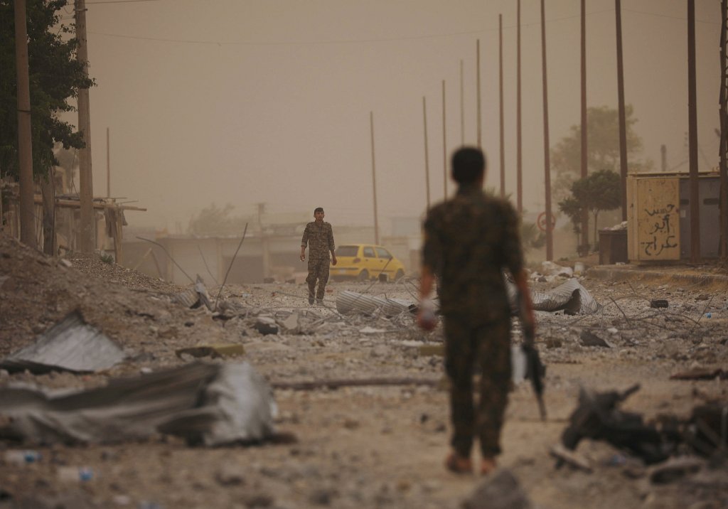 Syrian Democratic Forces (SDF) fighters walk on the rubble of a damaged street in the Raqqa's al-Sanaa industrial neighbourhood, Syria June 14, 2017. Picture taken June 14, 2017. REUTERS/Rodi Said
