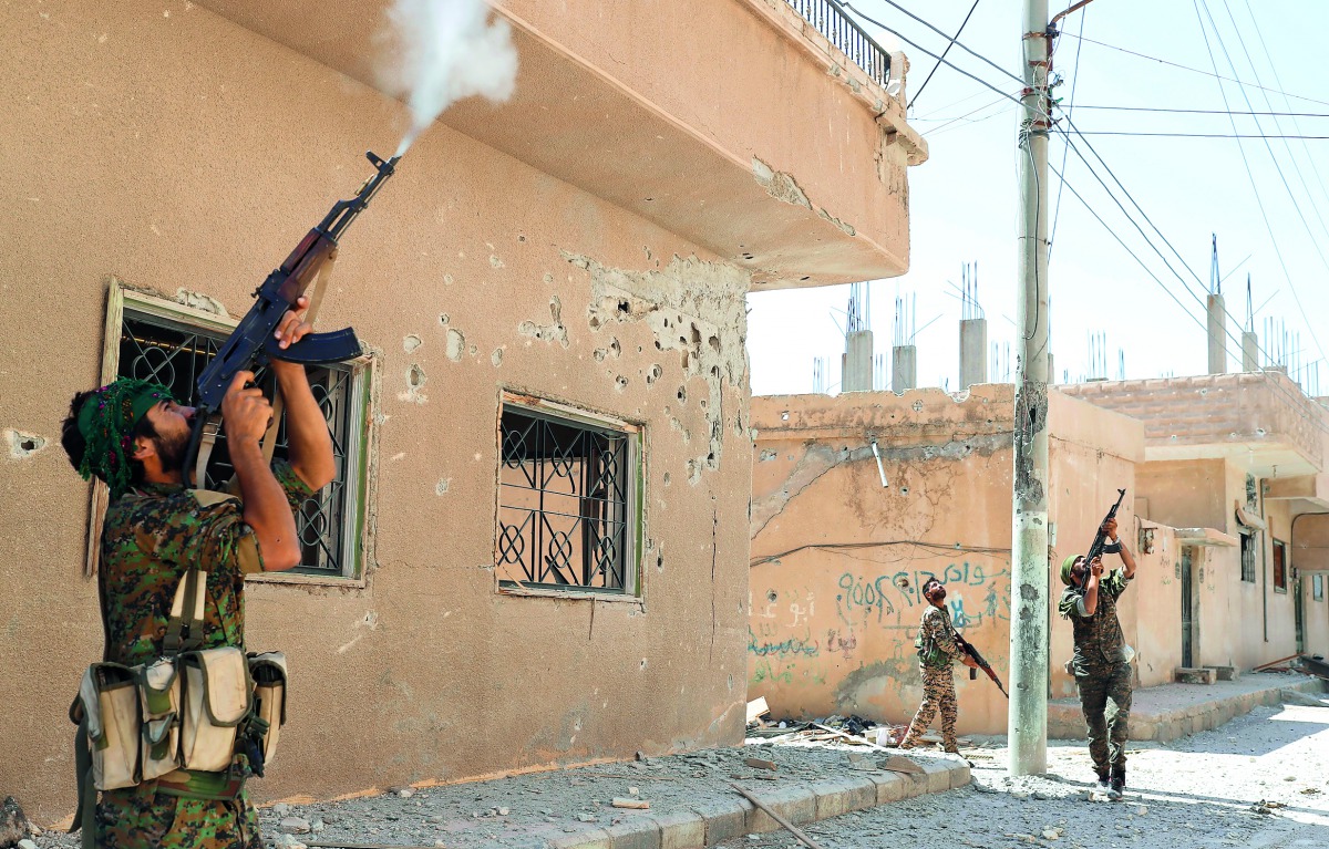 Kurdish fighters from the People's Protection Units (YPG) fires rifles at a drone operated by Islamic State militants in Raqqa, Syria, yesterday.
