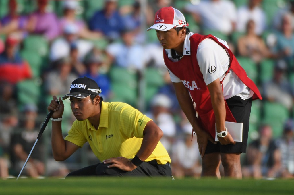 Hideki Matsuyama of Japan and caddie Daisuke Shindo lines up a putt on the 18th green during the second round of the 2017 U.S. Open at Erin Hills on June 16, 2017 in Hartford, Wisconsin. Ross Kinnaird/AFP

