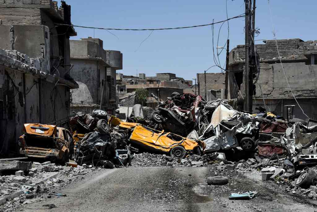 Damaged cars are seen stacked in the middle of a road in western Mosul's Zanjili neighbourhood on June 9, 2017, during ongoing battles to try to take the city from Islamic State (IS) group fighters. / AFP / MOHAMED EL-SHAHED