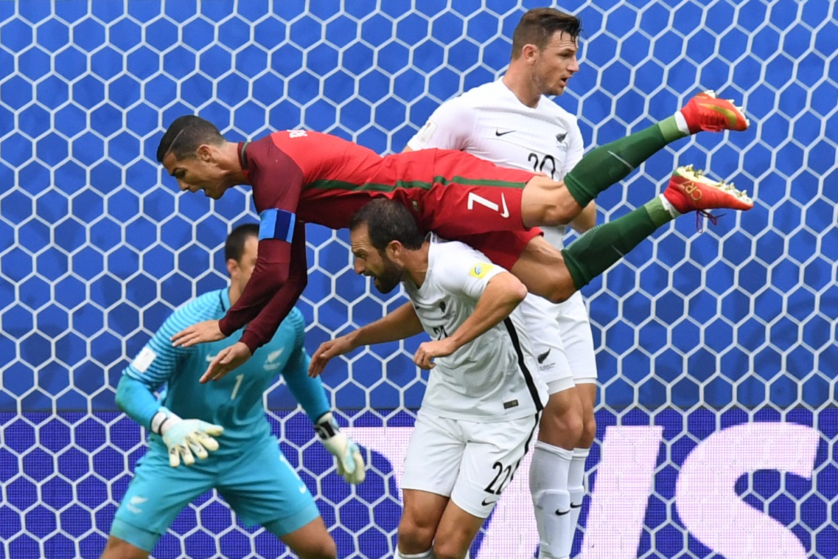 Portugal's forward Cristiano Ronaldo (L) falls over New Zealand's defender Andrew Durante after missing a goal during the 2017 Confederations Cup group A football match between New Zealand and Portugal at the Saint Petersburg Stadium in Saint Petersburg o