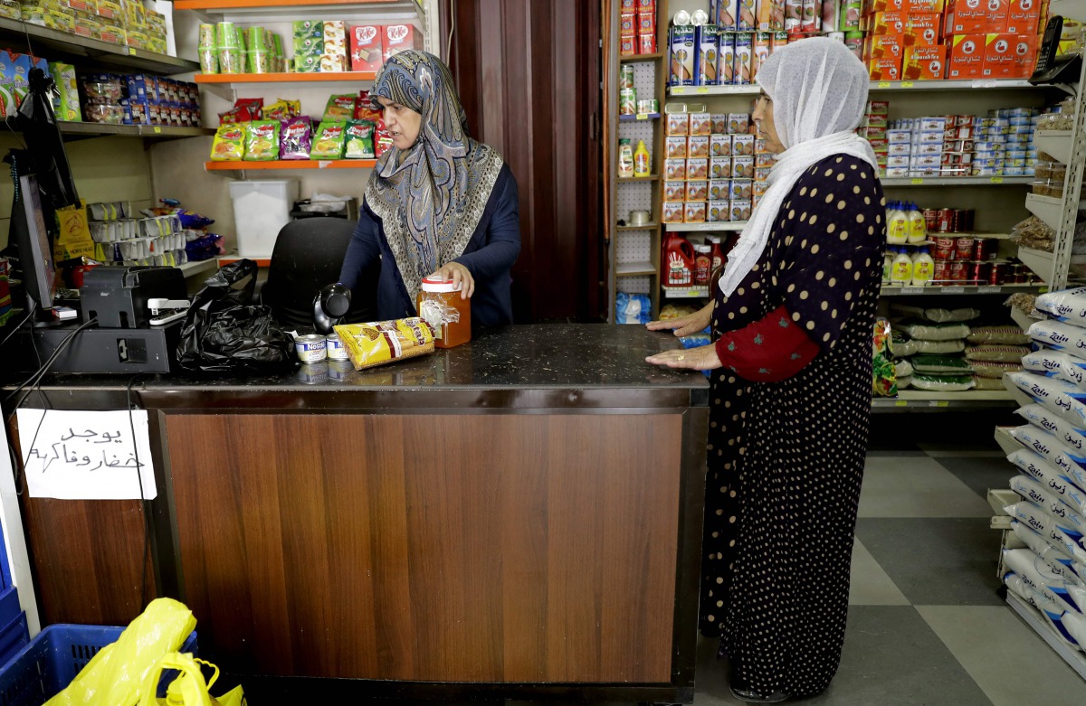 A Syrian refugee purchases goods at a shop, which accepts the United Nations' World Food Programme cards, in Beirut on June 14, 2017. Displaced Syrian families in Lebanon are using electronic cards, topped up each month by the United Nations' World Food P