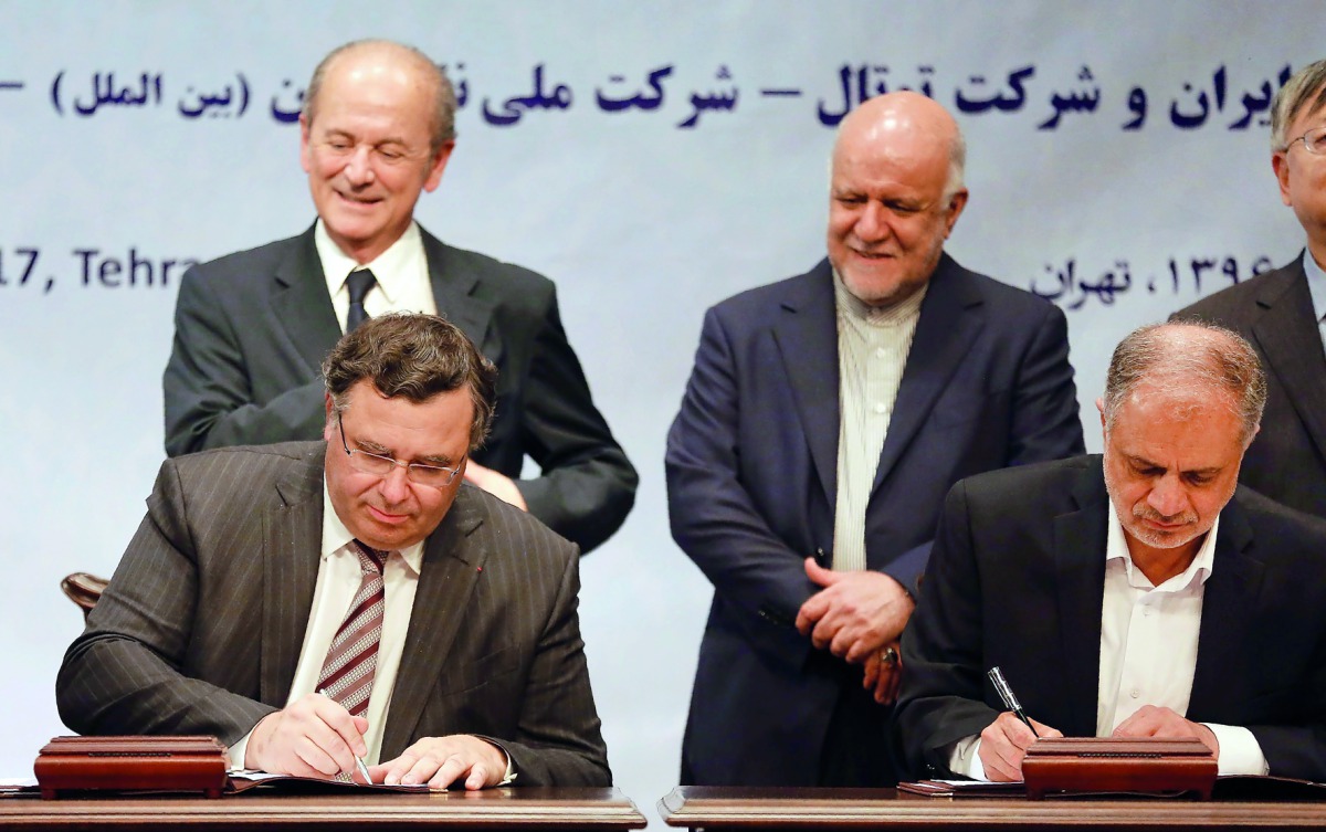 Iranian Oil Minister Bijan Namadar Zanganeh (C-R) looks on as Patrick Pouyanne (L), Chairman and CEO of French energy company Total, and Ezzatollah Akbari, Managing Director of Petropars Group, sign an offshore gas field agreement in Tehran, on July 3, 20
