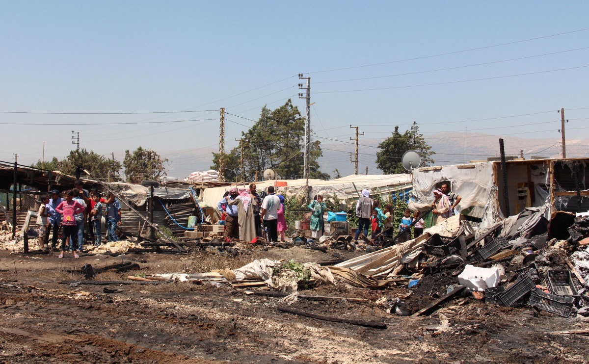 Syrian refugees look at the damage after a fire engulfed part of the Tel al-Sarhoun refugee camp near the village of Bar Elias in Lebanon's eastern Bekaa valley on July 4, 2017. (AFP / HASSAN JARRAH)