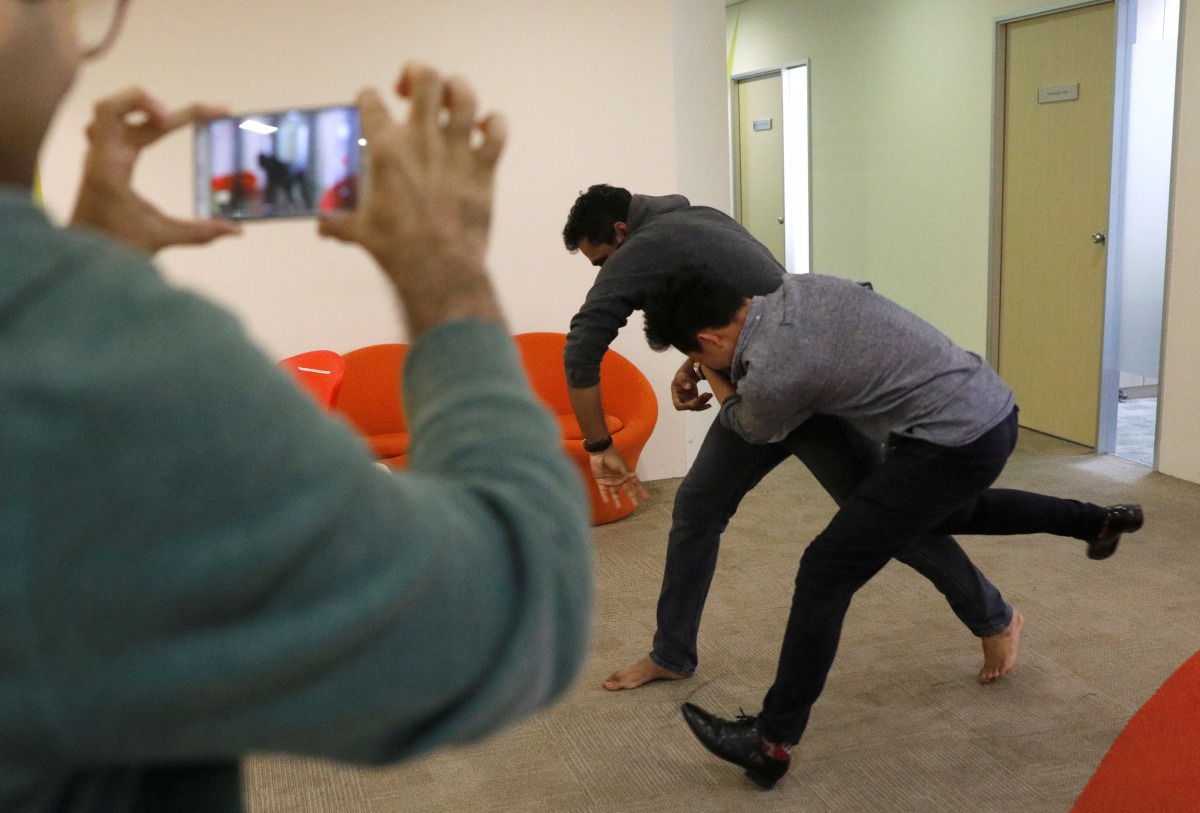Employees of Graymatics, a company known for its digital video analysis and image-recognition technology,  pretend to fight as they record footage to be used to train their software to watch and filter internet videos for violence at their office in Singa