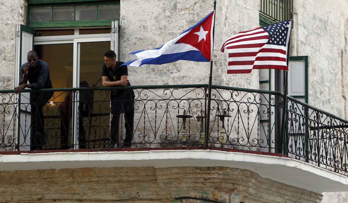 Two men stand on a balcony next to the Cuban and USA National Flags in Havana Cuba, March 17, 2016 (EPA / ERNESTO MASTRASCUSA) 