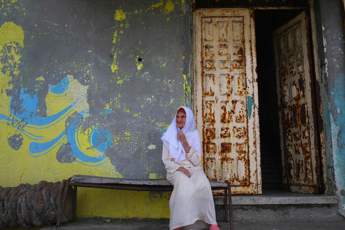 A Palestinian elderly woman sits outside her house at al-Shatee refugee camp during a heatwave in Gaza City on July 12, 2017. AFP / Mohammed Abed