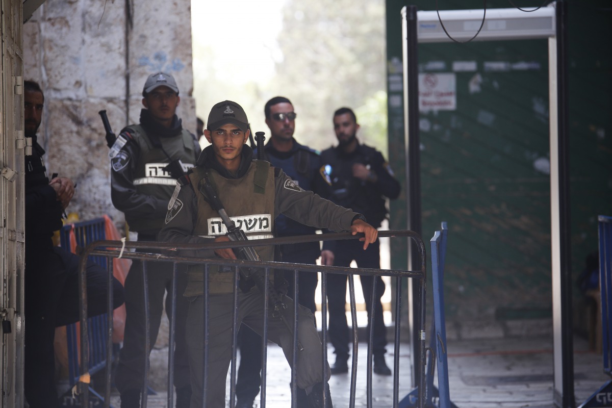 Israeli security forces wait as Palestinians perform prayer near new security metal detectors, outside one of the main entrances to the Al-Aqsa mosque, refusing to enter because of the detectors installed by Israel as the holy site re-opened for the first