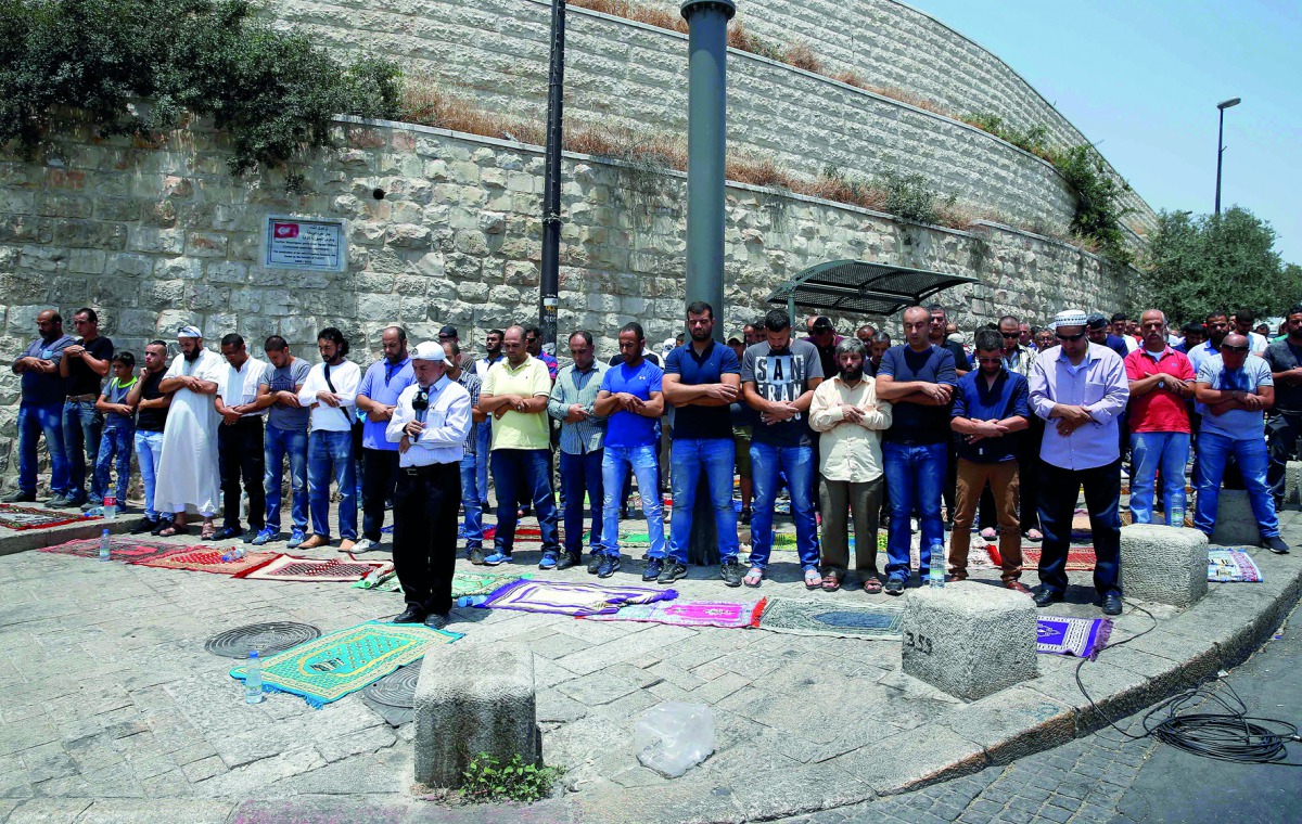 Palestinians pray outside Lions’ Gate, a main entrance to the Al Aqsa mosque compound in Jerusalem’s Old City, yesterday, in protest against new Israeli security measures implemented at the holy site the previous week. 

