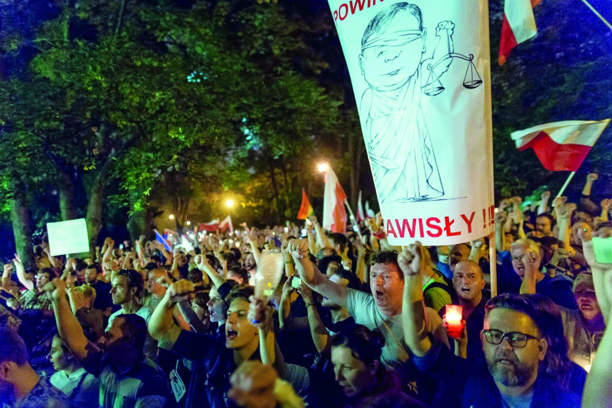 Protesters hold candles and shout slogans as they take part in a demonstration in front of the Polish Parliament.