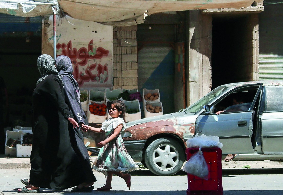 A Syrian girl holds a woman’s hand as she walks down a street in the central Syrian rebel-held town of Talbiseh, north of Homs, yesterday.