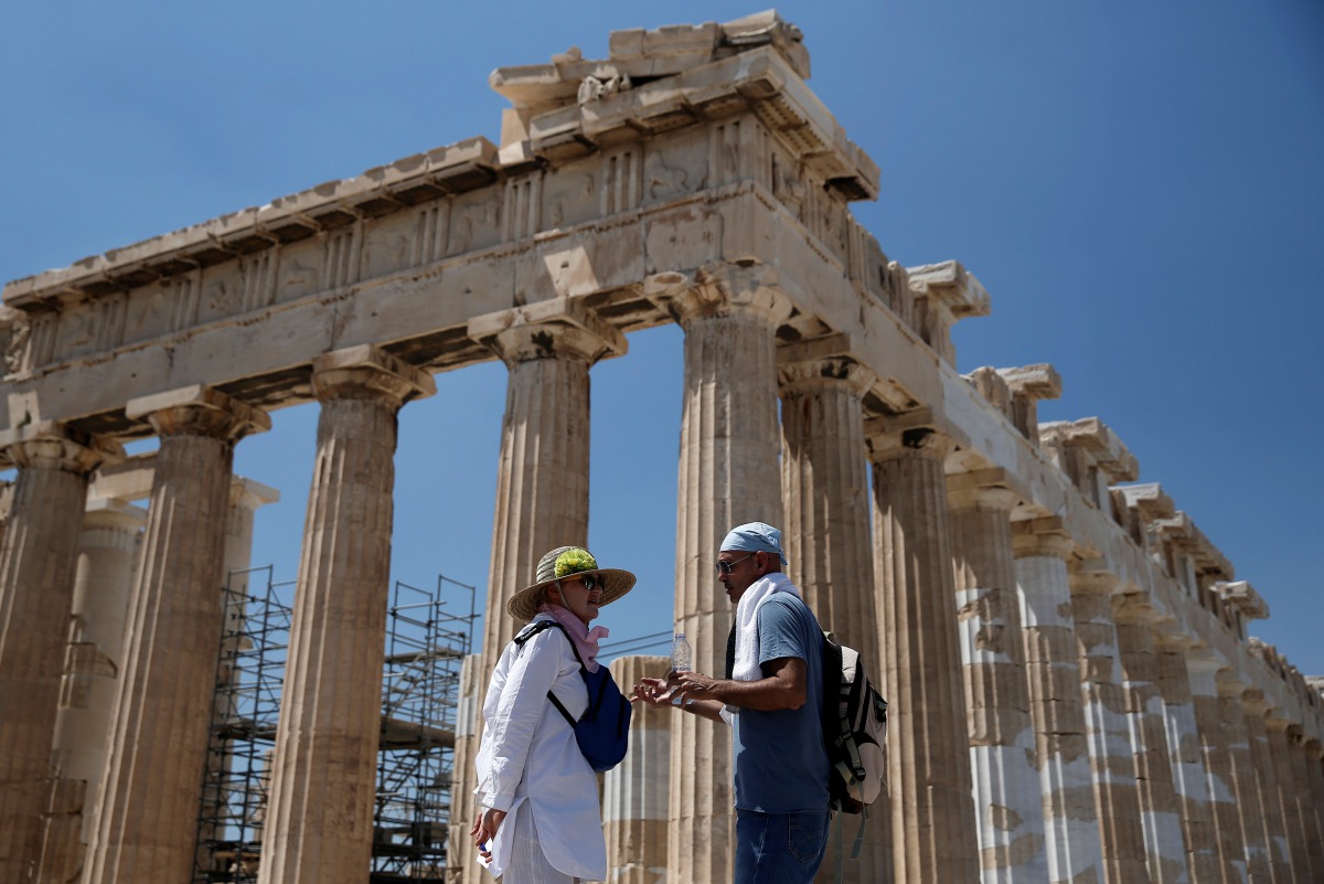Tourists stand in front of the ancient Parthenon temple atop the Acropolis hill in Athens, Greece August 5, 2017. Reuters/Costas Baltas
