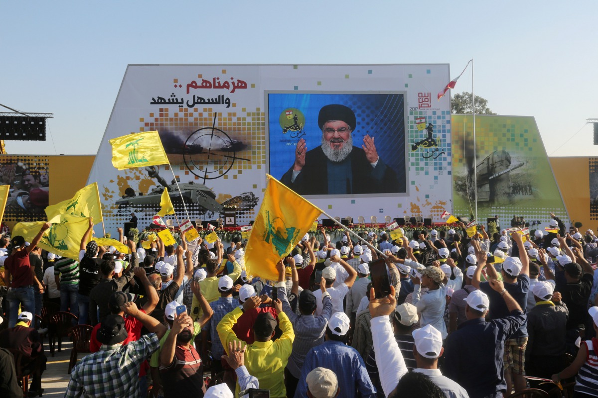 Supporters of Lebanon's Hezbollah leader Sayyed Hassan Nasrallah display Hezbollah and Lebanese flags as they listen to him via a screen during a rally marking the 11th anniversary of the end of Hezbollah's 2006 war with Israel, in the southern village of