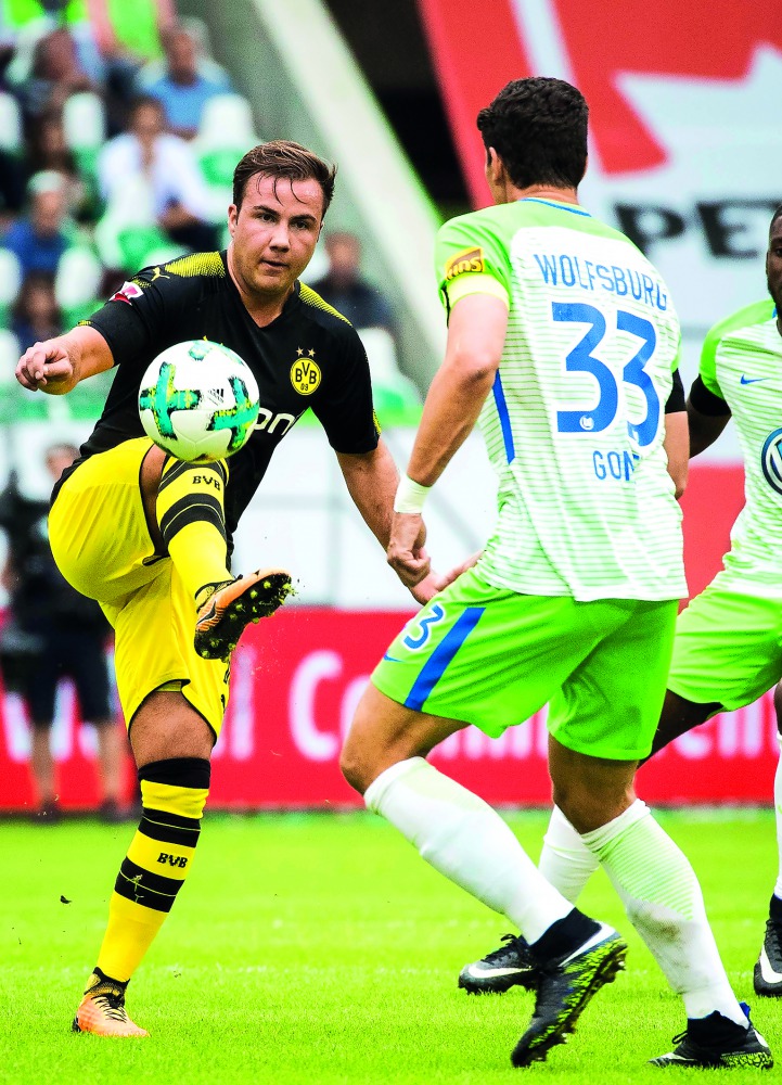 Dortmund’s midfielder Mario Goetze (left) and Wolfsburg’s forward Mario Gomez vie for the ball during their Bundesliga match  in Wolfsburg, western Germany yesterday. 