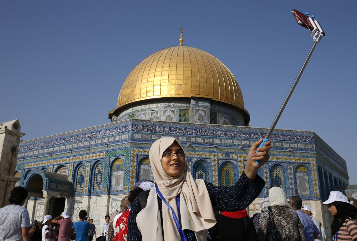 A Palestinian girl from the Gaza Strip takes a selfie outside the Dome of the Rock mosque in the Al-Aqsa mosque compound in Jerusalem's old city on August 20, 2017 as he visits the city for the first time as part of an exchange programme run by the UN age