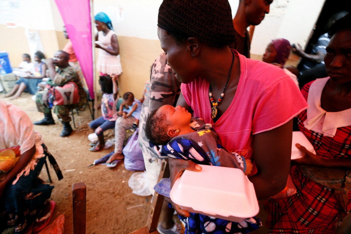 A mother, with her baby, picks up food at the internally displaced persons camp in Regent, Sierra Leone August 19, 2017. Reuters/Afolabi Sotunde