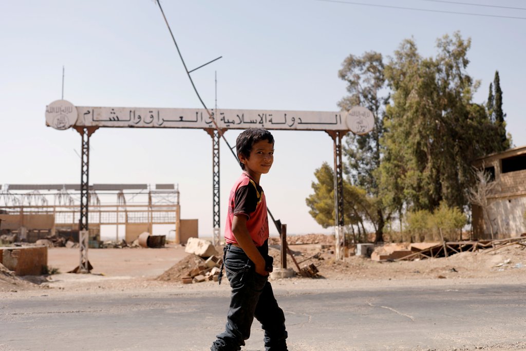 A boy walks past a sign which reads 'Islamic State in Iraq and Syria' as fighting continues between the Syrian Democratic Forces and Islamic State militants in Raqqa, Syria, August 20, 2017. REUTERS/Zohra Bensemra
