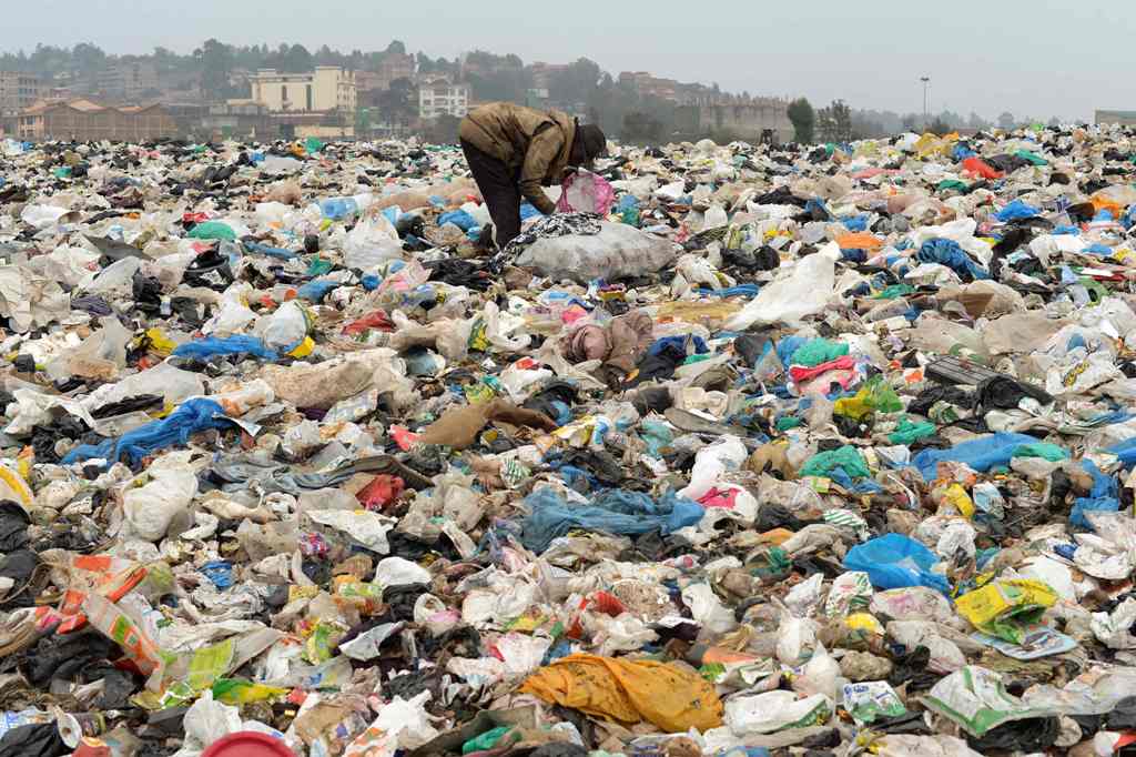 A man searches through waste at the Ngong town dumping site, 30 kilometres southwest of Nairobi, on August 24, 2017. AFP / SIMON MAINA
