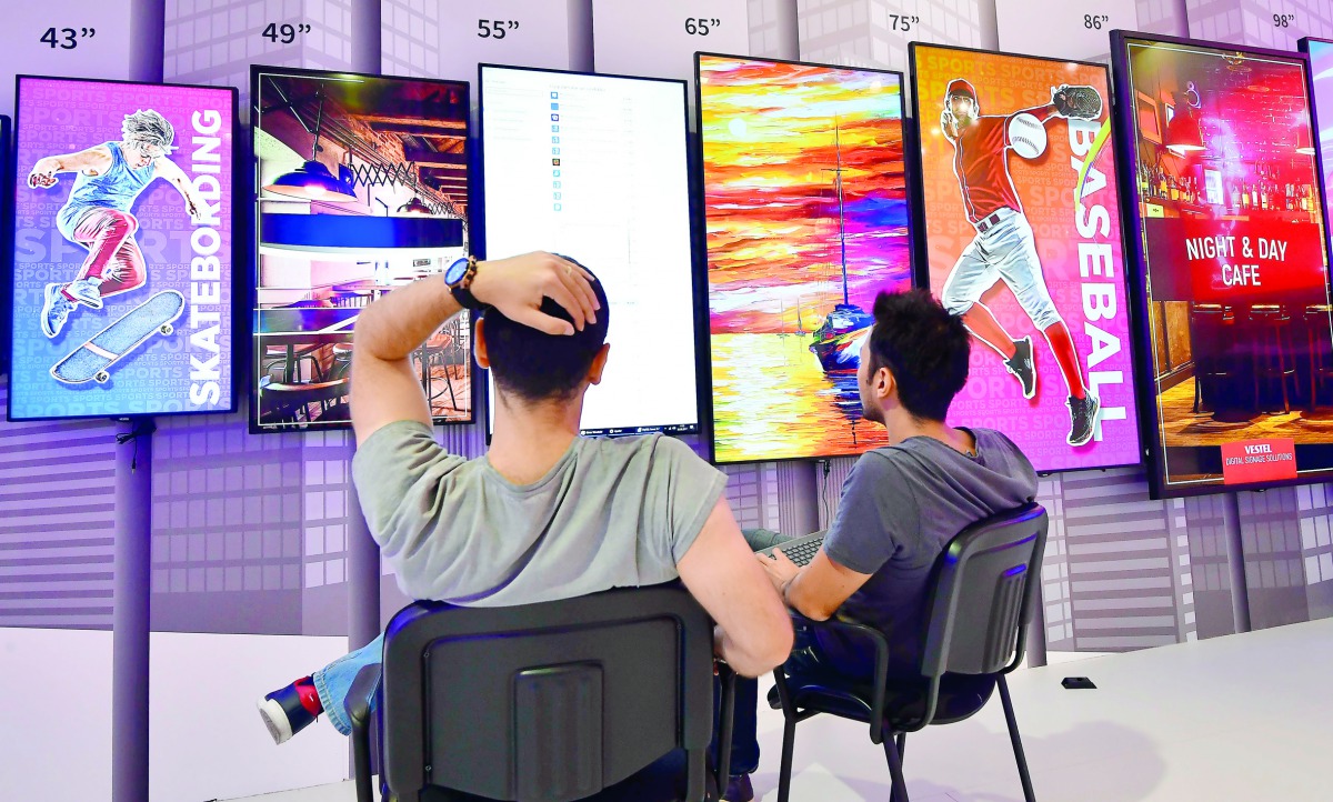 Two men sit in front of television screens on display at the booth of Vestel as preparations are under way for the consumer electronics fair IFA in Berlin on August 30, 2017. The fair is open for the public from September 1 to 6, 2017.  AFP / Tobias Schwa