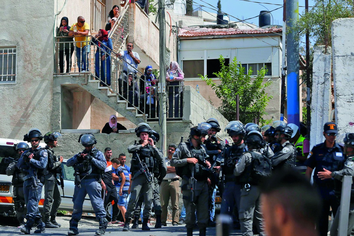Israeli security forces and Palestinian residents watch as the home of the Abu Farah family is demolished by municipality workers at Al Tur, yesterday.
