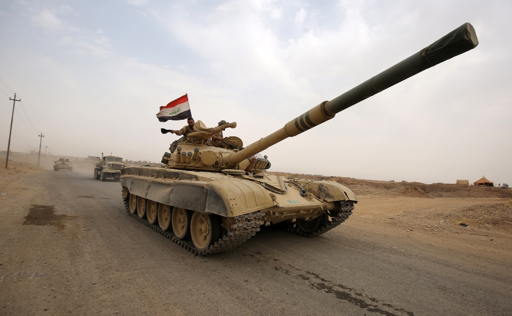 An Iraqi soldier waves his hat from the turret of a Russian-made T-72 tank, as Iraqi forces advance towards the city of al-Sharqat on September 20, 2017, where Iraqi forces backed by Hashed al-Shaabi (Popular Mobilisation) paramilitaries are preparing to 