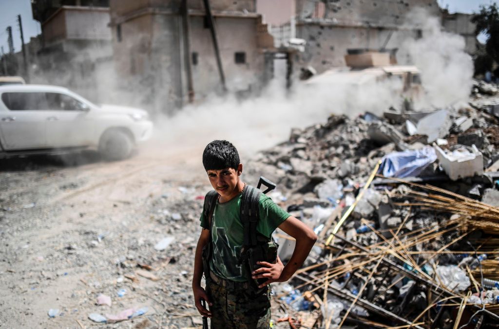 A member of the Syrian Democratic Forces stands on a damaged street on the eastern frontline of Raqa on September 24, 2017.   AFP / BULENT KILIC
