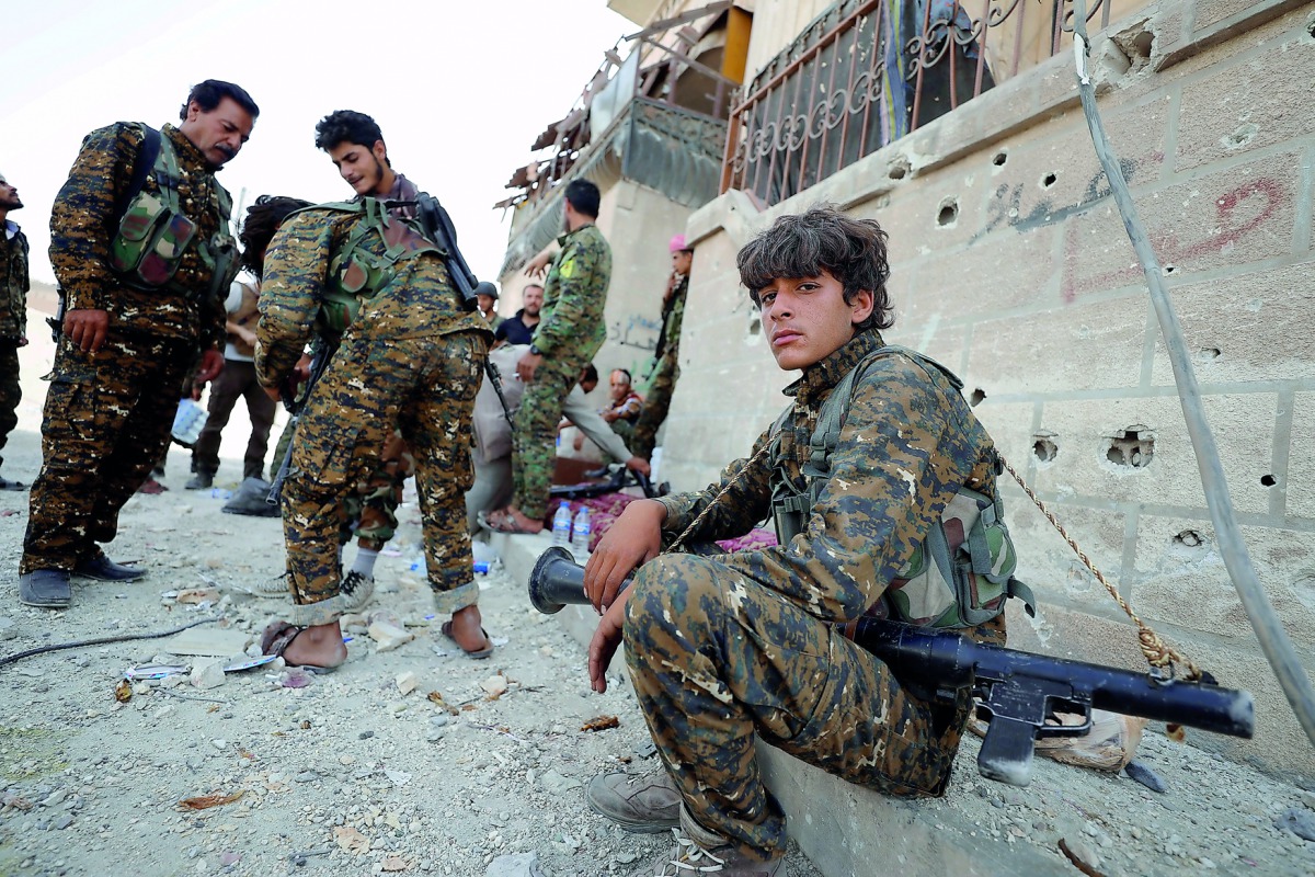 A fighter from Syrian Democratic Forces (SDF) sits on a curb as he holds his weapon in Raqqa, yesterday.